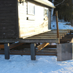 A wooden deck in the snow near a house.