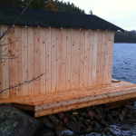 A wooden structure sitting on top of rocks near water.