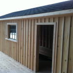 A wooden building with a door open and windows closed.