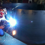 A person welding in the dark with blue light.