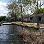 A lake with houses on the shore and trees in front of it.