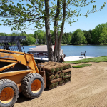 A tractor parked next to a lake with trees.