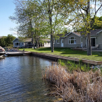 A lake with houses in the background and trees.