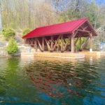 A red roof covered dock in the middle of water.