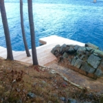 A dock with rocks and trees in the background